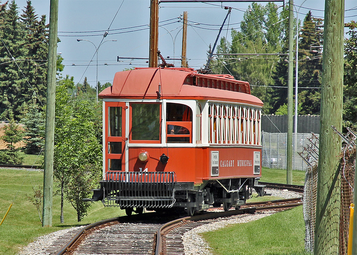 On a beautiful sunny morning Heritage park tram #14 makes its way around the lake and parking lot taking passengers to the Park's main entrance.  The tram comprises a replica body riding on original street car #14 chassis.