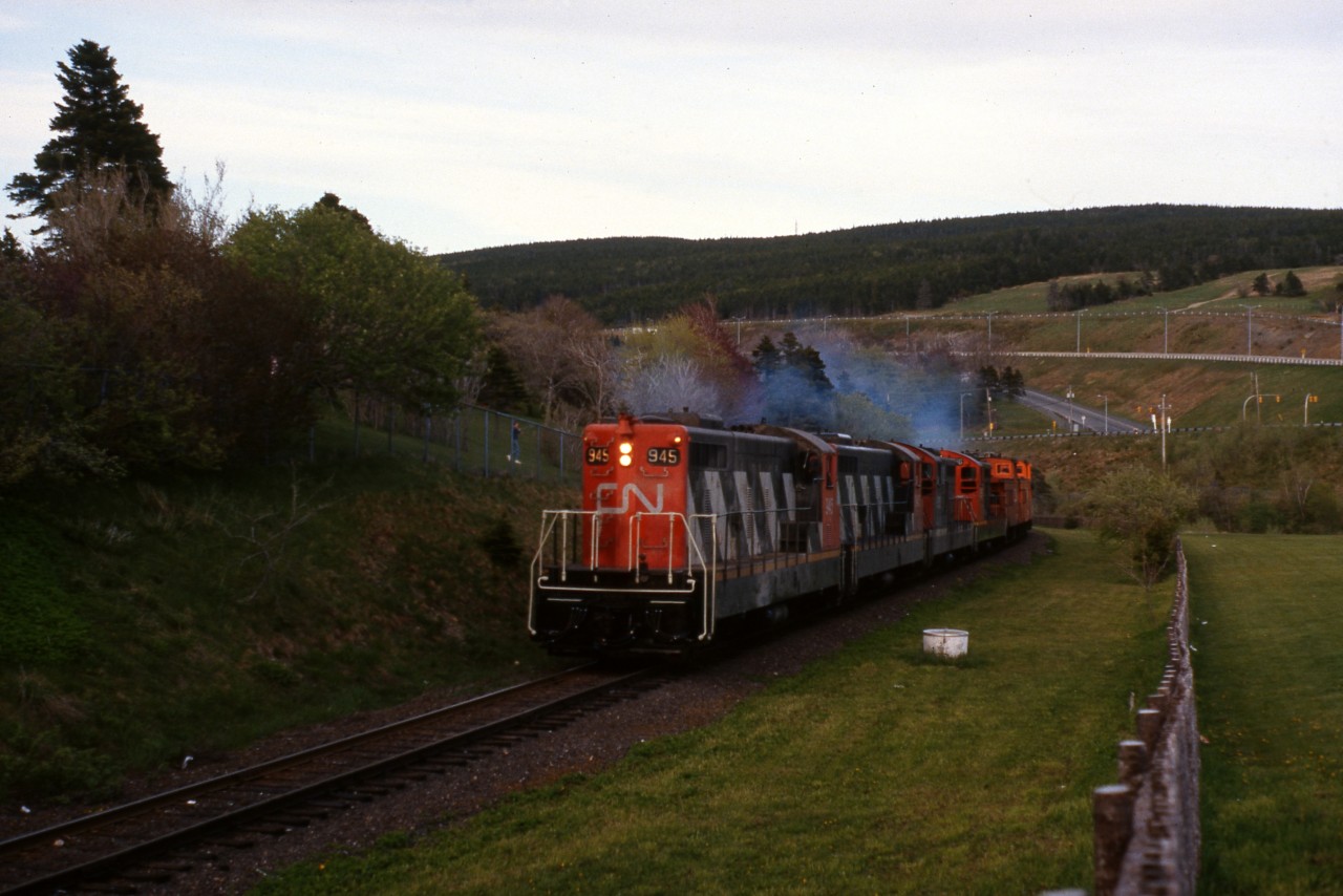 TWILIGHT ON THE ROCK - Terra Transport Extra 945 West runs upgrade through Bowring Park in the center of St. John's with just barely enough light to capture this image. A daily scheduled 547 mile run to Port aux Basques, this time it left the capital city with a unique consist of only four 1200 horsepower units and two cabooses. Upon arrival at Bishops Falls early the next morning, it would pick up a coach (and in all likelihood several empty containers at Grand Falls) making it a mixed run to Corner Brook.