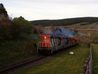 TWILIGHT ON THE ROCK - Terra Transport Extra 945 West runs upgrade through Bowring Park in the center of St. John's with just barely enough light to capture this image. A daily scheduled 547 mile run to Port aux Basques, this time it left the capital city with a unique consist of only four 1200 horsepower units and two cabooses. Upon arrival at Bishops Falls early the next morning, it would pick up a coach (and in all likelihood several empty containers at Grand Falls) making it a mixed run to Corner Brook. 