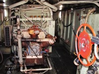 Here is the view looking in from the rear door of a red barn SD40-2F. 3 cylinder air compressor in front with water temperature header directly above. To the right the handbrake wheel and corridor leading to the entry of the engineer's side of the cab.
