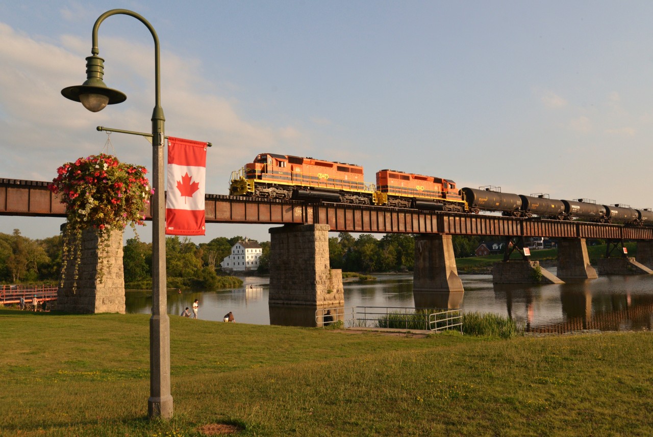 With pristine RLHH 3404 in the lead, RLHH 597 daily freight trundles across the Grand River Bridge at Caledonia in good light on a colourful, inviting Fall evening enroute to interchange at Brantford/Paris. This particular evening set the stage with an earlier than normal crossing, soft lighting, clear reflections, historic backdrop and fishing enthusiasts.