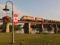 With pristine RLHH 3404 in the lead, RLHH 597 daily freight trundles across the Grand River Bridge at Caledonia in good light on a colourful, inviting Fall evening enroute to interchange at Brantford/Paris. This particular evening set the stage with an earlier than normal crossing, soft lighting, clear reflections, historic backdrop and fishing enthusiasts. 