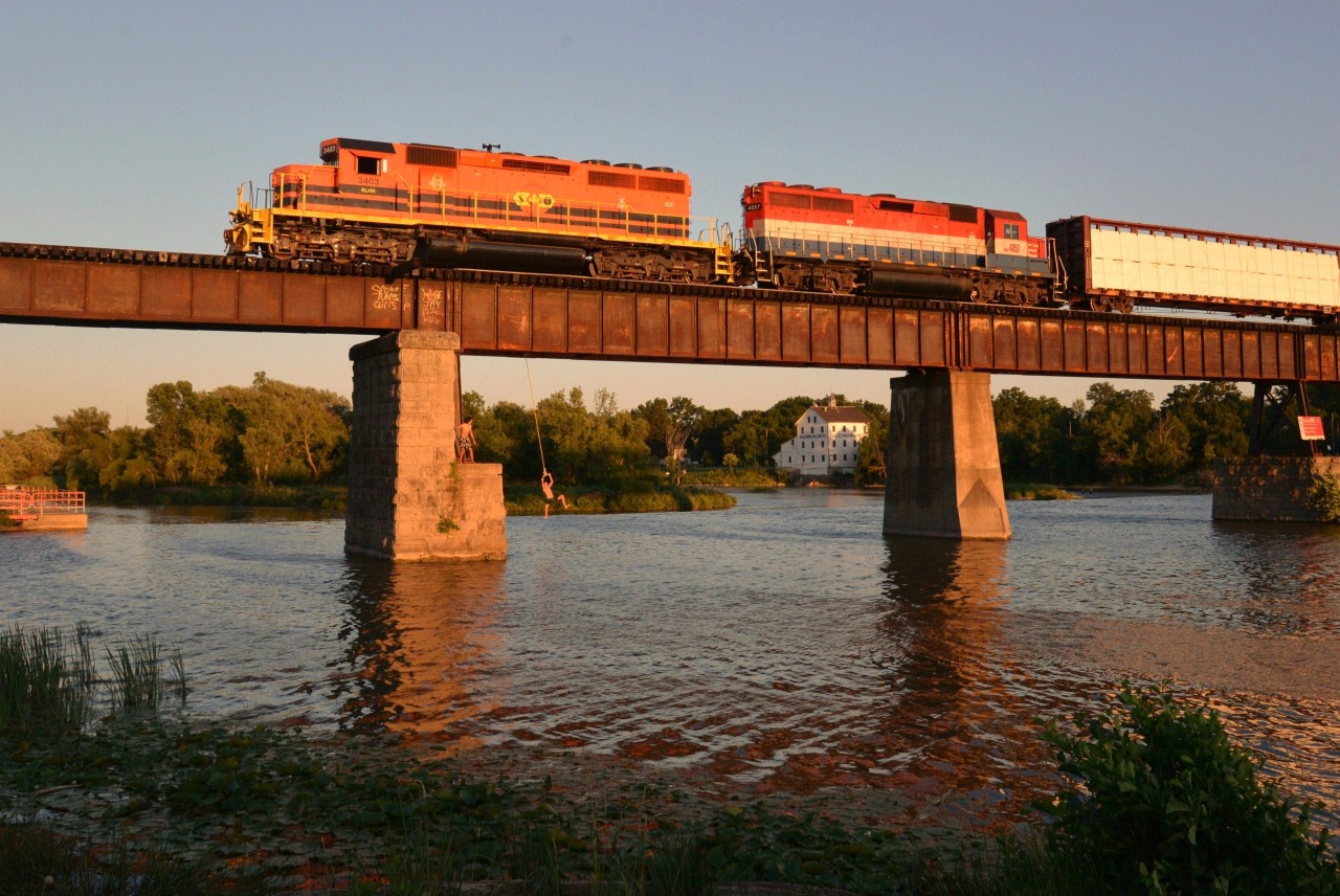 Boys will be boys!  Even though a new, modern pool with life guards exists nearby at the east end of this fully facilitated park, these young lads (and others) choose this more daring form of enjoyment.  Their fun is not interrupted in the least by RLHH 597 as it slowly rumbles over the iconic structure spanning the Grand River at Caledonia. On this warm summer evening, RLHH 597 is powered by RLHH 3403 in G&W livery and SOR 4057 still in RailAmerica stable.