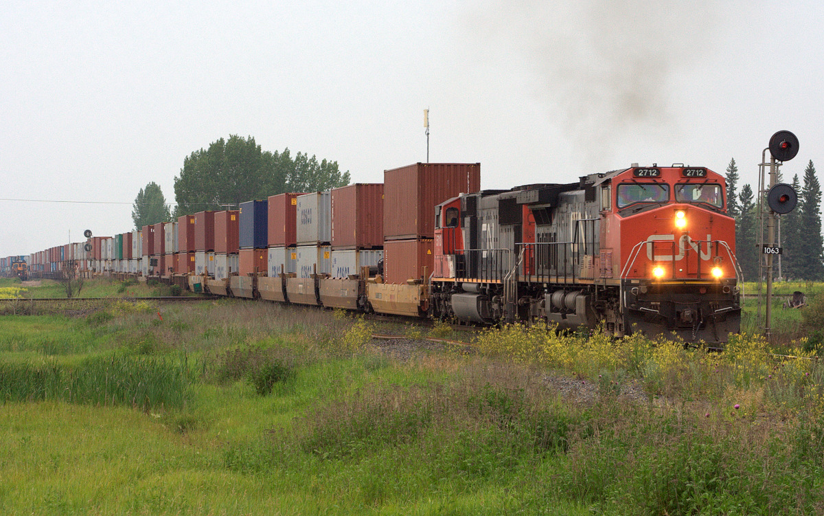 With all the smoke from the fires and a thunderstorm, you wouldn't think its 5 pm in July. CN 2712 departs after waiting for a southbound CP potash train and a westbound CN inter modal.