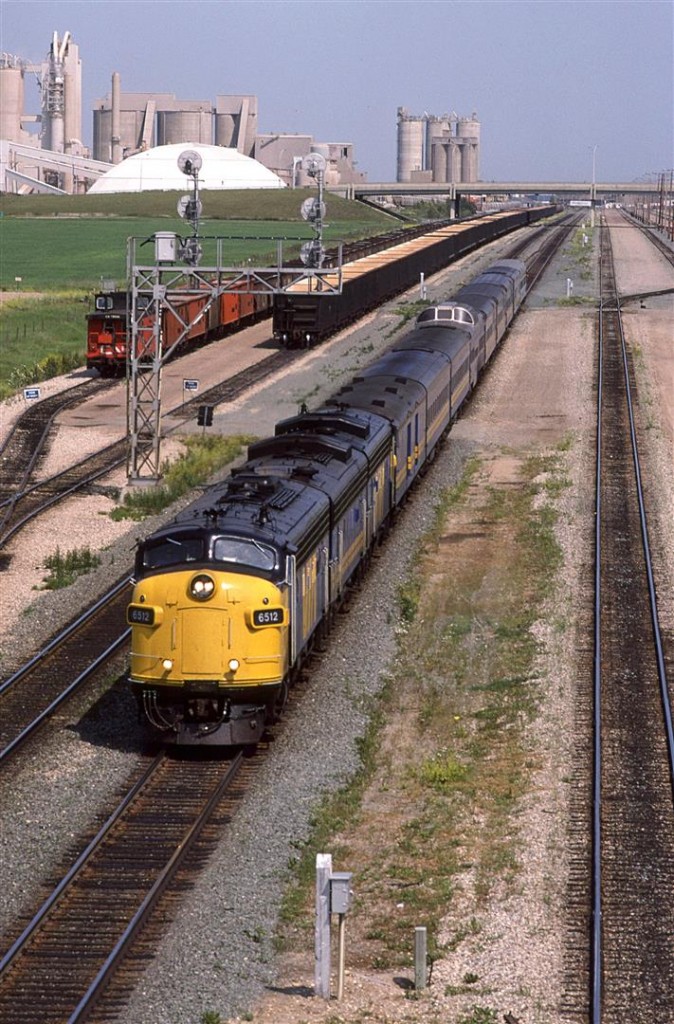 A 135mm lens view of the westbound "Super Continental" passing through Bissell yard. A lot has happened since the noon hour (This short was taken at 1452hrs). The track to the south cleared out and an empty welded rail train arrived. The Sulphur cars, however remain.
That is Inland Cement dominating the background.