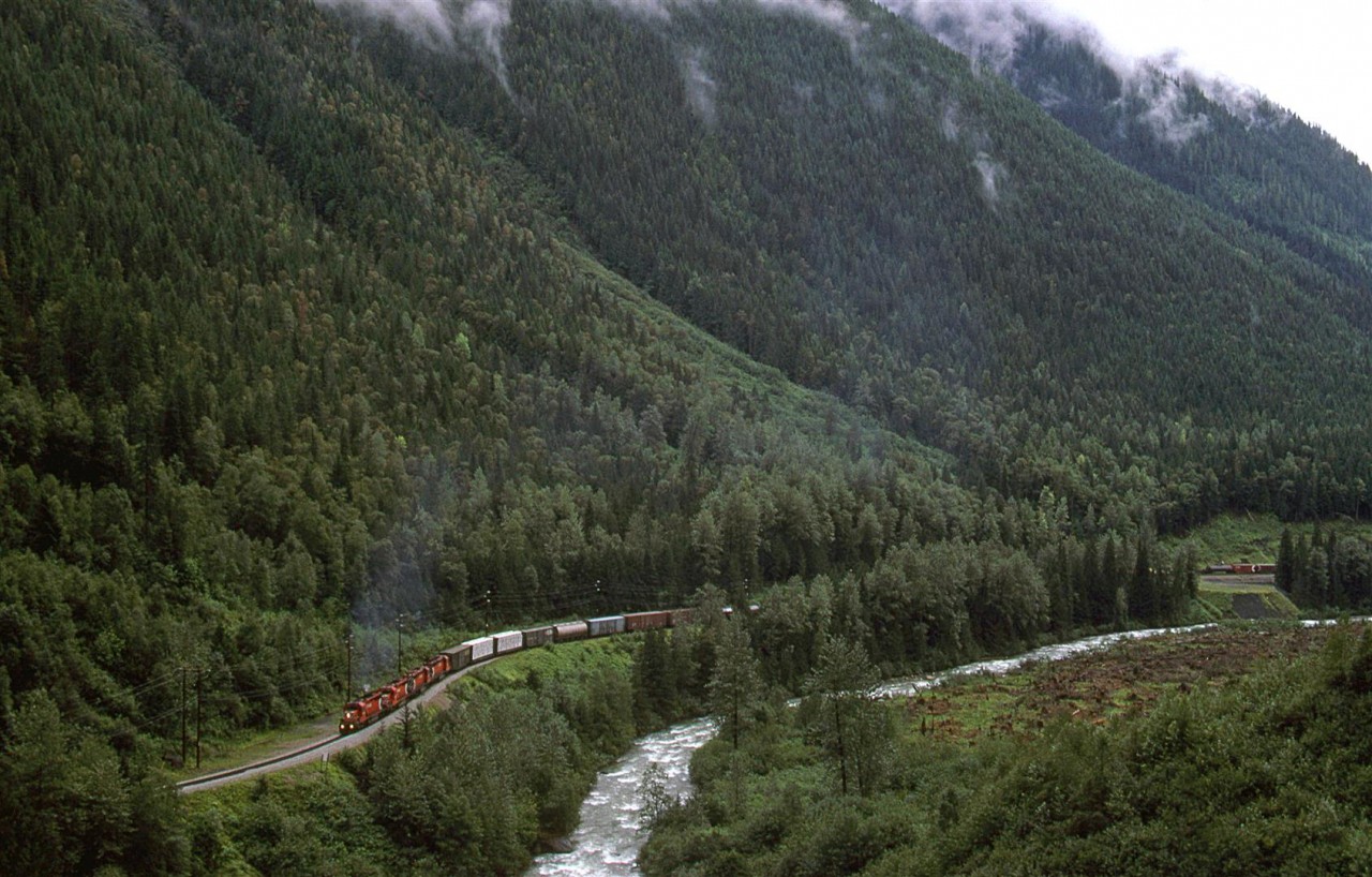 This view is almost obscured too, however, there are likely ways that it couyld be had from a slightly higher vantage point.
The eastbound manifest is through Illecillewaet siding, but still has several more Kilometers to go before the engineer can slack off on the power at the crest of Rogers Pass.