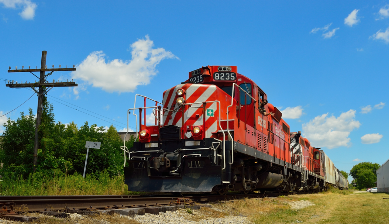 OSR's daily way freight heads north with several cars and the van behind a pair of ex CP London built GP9's past mile 31 of the old CP Goderich Sub, while conductor Da Costa waves from the cab.