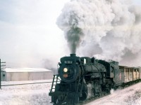 With livestock cars and a reefer at the head end, Canadian National S1g-class Mikado 3518 leads a northbound freight on the CN Brampton Sub through the Mount Dennis area of York Township, about to cross the Eglinton Avenue level crossing (near the old Kodak plant, which was out of frame to the left) in 1959. CP's MacTier Sub can be seen running parallel in the background. At this time, Mount Dennis was part of York Township, and had joined the Municipality of Metropolitan Toronto only a few years prior.<br><br>At present, this single track line (renamed from the Brampton Sub to the Weston Sub in 1965) has become a multi-track corridor owned by Metrolinx, used by GO Transit, VIA and the Union-Pearson Express passenger trains, and the level crossing at Eglinton has long since become an underpass (mid-60's). Kodak closed in the mid 2000's and the factory was demolished, but a station along the Eglinton Crosstown LRT is planned for this location to connect to passenger rail traffic.