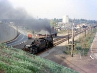 As a follow-up from the previous image of the <a href=http://www.railpictures.ca/?attachment_id=25189><b>steam-powered westbound at Cooksville</b></a>, here's a general overview of the Canadian Pacific's Cooksville Station area looking northwest from the top of the Highway 5 / Dundas Street East overpass in 1957. CPR D10 882 has just passed under the overpass and is heading west on the Galt Sub past the old wooden Cooksville Station (note the old red CP Express truck parked outside). In the background is the S.H. Dellow Block and Builders supply plant, a longtime local maker of concrete blocks (with a siding for rail service).
<br><br>
<i>More Cooksville</i>: CPR doubleheader passing the Cooksville Brick plant further down the line: <a href=http://www.railpictures.ca/?attachment_id=14123><b>http://www.railpictures.ca/?attachment_id=14123</b></a>
"   height=