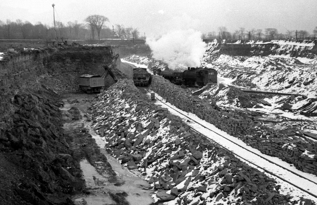 The Cooksville Brick Company (opened in 1912 as the National Brick Co.) operated a large brick manufacturing plant and quarry north-east of Highway 5 (Dundas) and Mavis in Cooksville, located off the south side of CP's Galt Sub at Mile 16.02. Around a half a dozen small steam tank engines and a gas Whitcomb switcher were used in the quarry pit to move excavated material to the plant, as seen here working during their final year of switching the pit. Ground level photos taken that day were rushed, being told by employees to leave as it was dangerous (in hindsight, they were right!).

Cooksville Brick sold all their small engines in 1955 when they switched to using trucks in the quarry pits, and used a trackmobile to switch the remaining plant tracks. The plant and quarry were closed under Domtar ownership in 1995, and the site has since been redeveloped into a suburban Mississauga neighbourhood (with a number of quarry-themed streets).