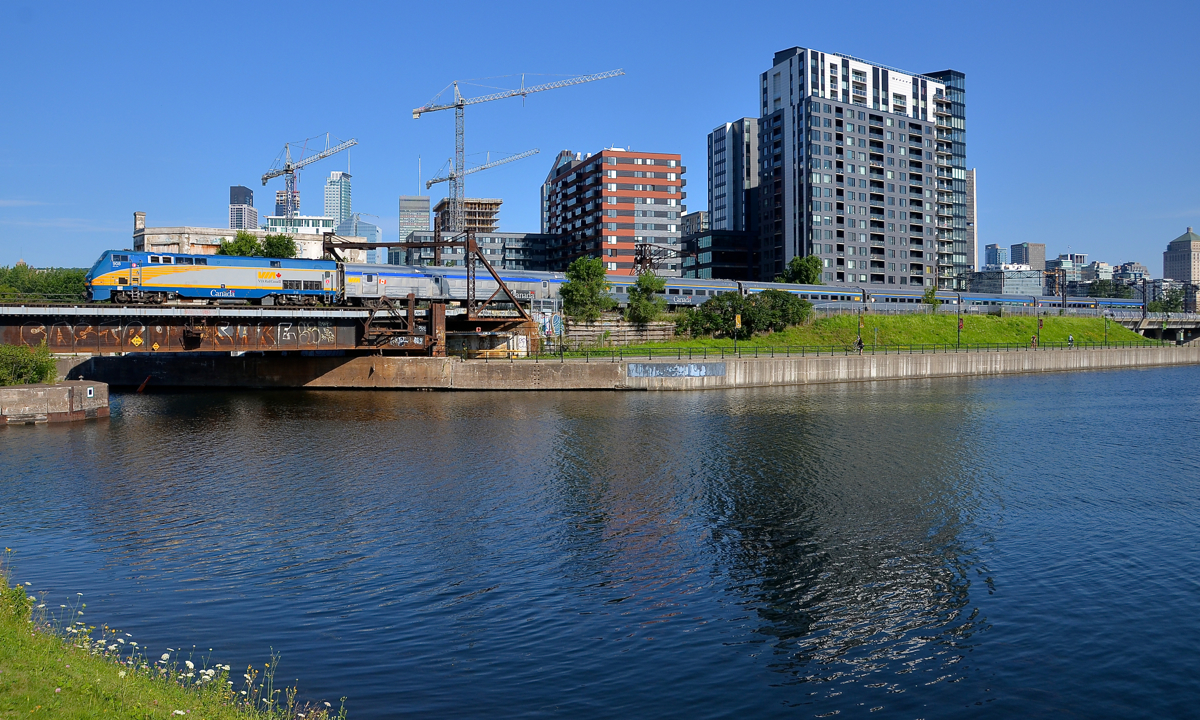 100% stainless steel. For quite some time VIA 63 was running with a single LRC among 5-6 stainless steel cars. Since the June 1st VIA Rail schedule changes it has been running with a 100% stainless steel consist. Here it passes Montreal's skyline five minutes after leaving Central Station with seven stainless steel cars in tow. Click here for an example of how VIA 63 looked with a single LRC car in the consist.