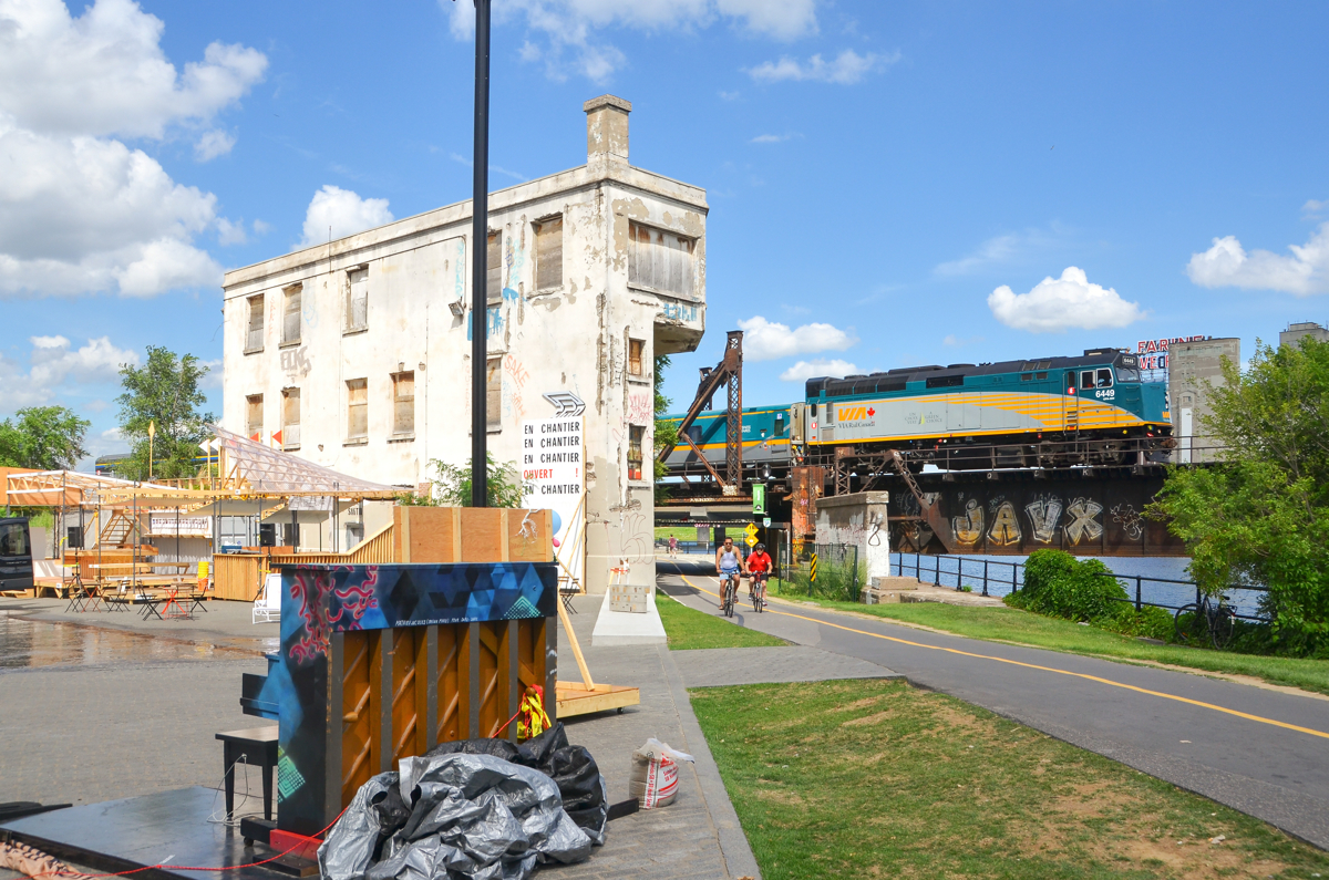 A tower, a piano and a VIA Rail train. VIA 635 is seen passing Wellington tower five minutes after leaving Central Station in Montreal with VIA 6449 leading. In the foreground is a piano, part of the city of Montreal's 'public piano' program.