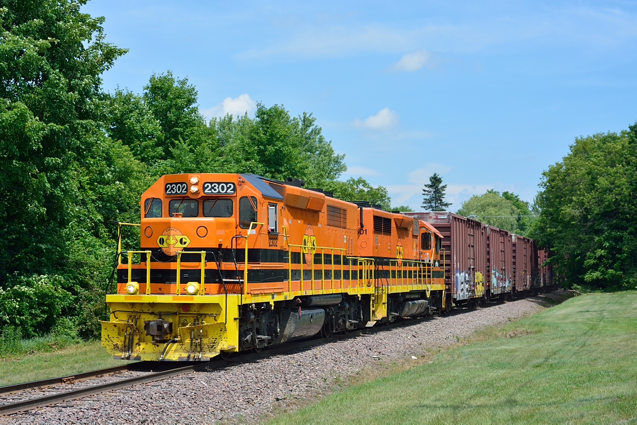 The westbound Quebec Gatineau freight on the Lachute sub approaches the town of Lachute on a sunny July afternoon.