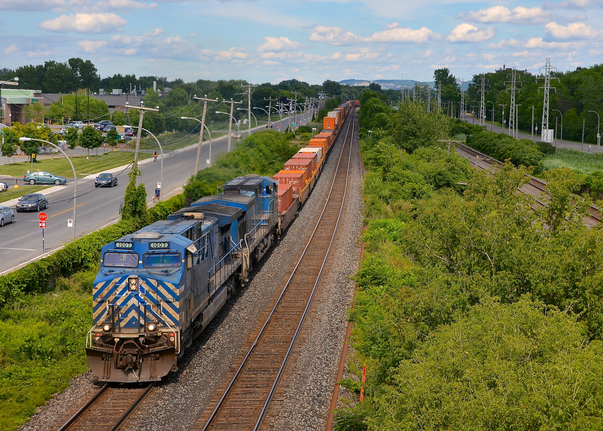 A pair of consecutively numbered Bluebirds. CEFX 1007 & CEFX 1006 lead CP 143 through Pointe-Claire just as the sun comes out and illuminates most of the train.