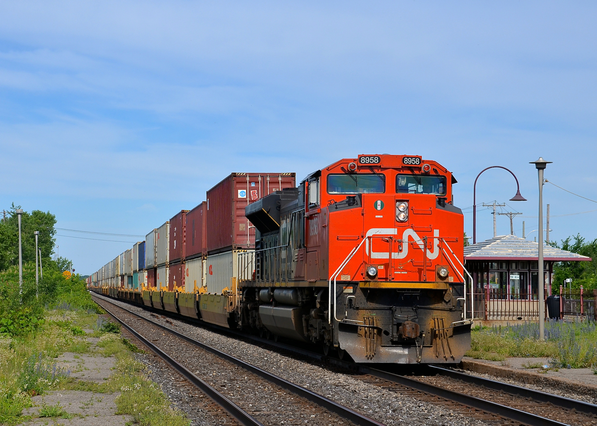 In from the west coast on Canada Day. On Canada Day, CN 106 is nearly finished its continentwide trek from Roberts Bank near Vancouver, BC as it approaches its terminus of Taschereau Yard in Montreal. Up front is CN 8958, with CN 2834 operating mid-train.