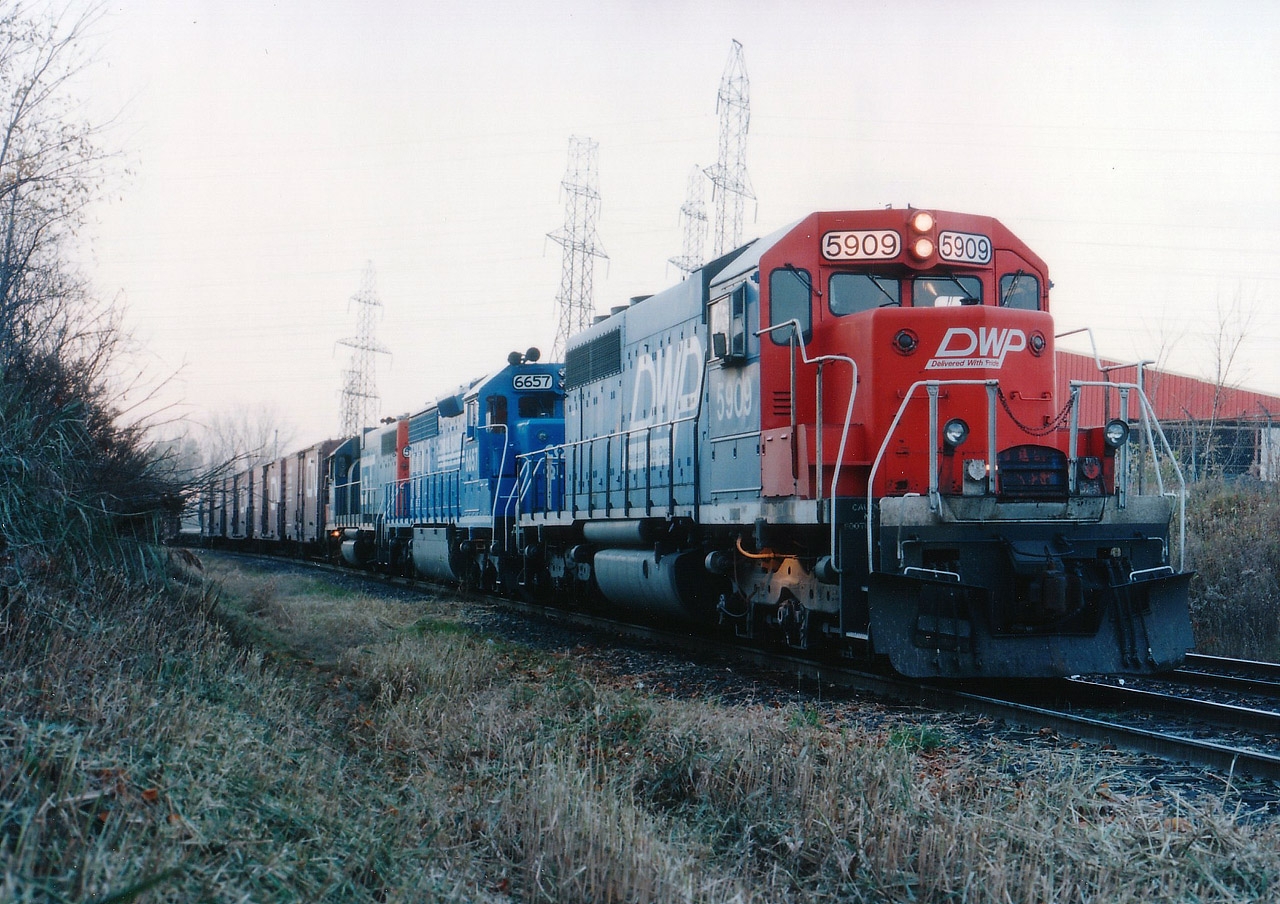This so-so November afternoon actually started off as a quest to find #328, which was down in the Welland area. Upon success, and return, I did my shopping/snooping and heard #333 over the scanner being held at mile 2.8 Grimsby sub. It was late in the day and in November the sun sets early. I parked at Whirlpool and Stanley Av as I could see the train almost around the bend from the road. Walked in. Quite the surprise it had a Duluth, Winnipeg & Pacific on the lead. Rare thing in these parts. And only 10 of these SD40s on the roster to begin with. The light was so bad that I had to find an old board and use it for a monopod in order to get a shot of this train with the Mamiya 645. I have 400 ISO film and couldn't even get a reading. This is the result of "board-held" effort for 8 seconds set at 5.6 for some sharpness. Lost a bit of colour but at least I did not blur the shot while counting off the time.
DW&P was CN's connection to Duluth, MN from Fort Frances, ON. The road existence began between 1901-1908; it was originally the Duluth, Virginia & Rainy Lake. Taken over by CNoR (Canadian Northern) which in turn went bankrupt and was taken over by CN. This subsidiary line had its identity eliminated for the most part when CN began in 1994/95 to put all locos under one banner, which was 'CN North America'. However, the DWP for all intents and purposes still exists.
Quite the lashup this was: DWP 5909, CR 6657 and GT 5806. A real CN treat.