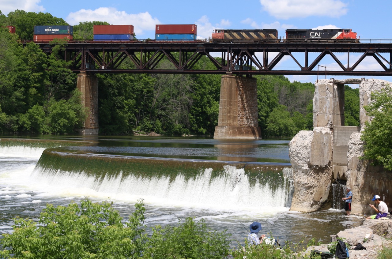 One of CN's last and first DC models built by General Electric roll intermodal train #148 high above the fishermen and the unique "S" shape dam along the Grand River at Paris.