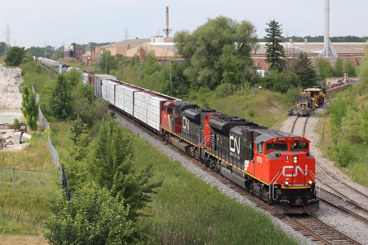 The heat and humidity is no factor for the crew of not so common train 523. The train has just crossed Bronte Creek on the single track bridge at Tansley in the distance. To the right is the brick works facility, which from time to time still sends out boxcar loads from the loading dock to the right. On this day CN had MofW equipment stored on the stub track.
