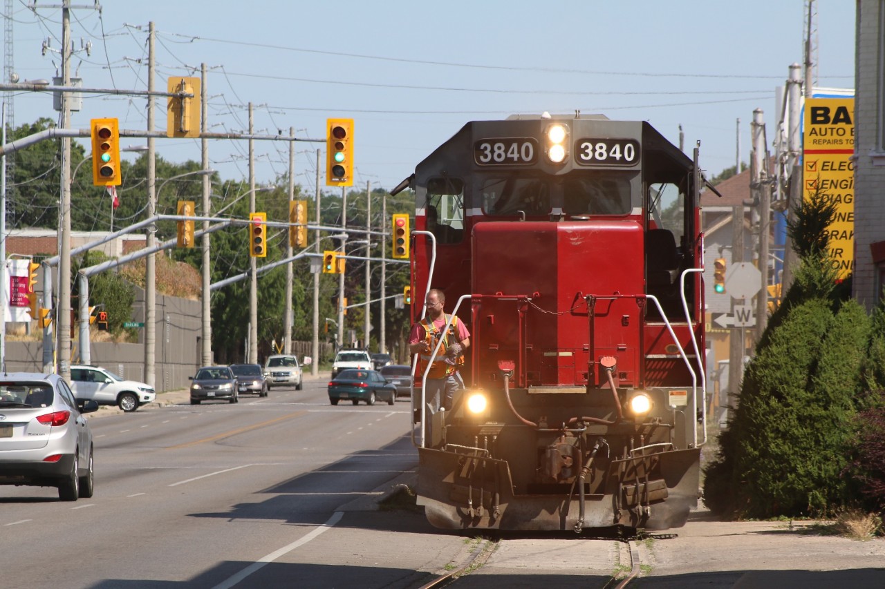 SOR's once a week train to serve the last customer on the Burford spur is seen polishing the rails in Clarence Street as the brakeman keeps a watchful eye on vehicular traffic. The Gp38 is unique in that it is one of only a few built with an extended cab allowing for a dual control stand.