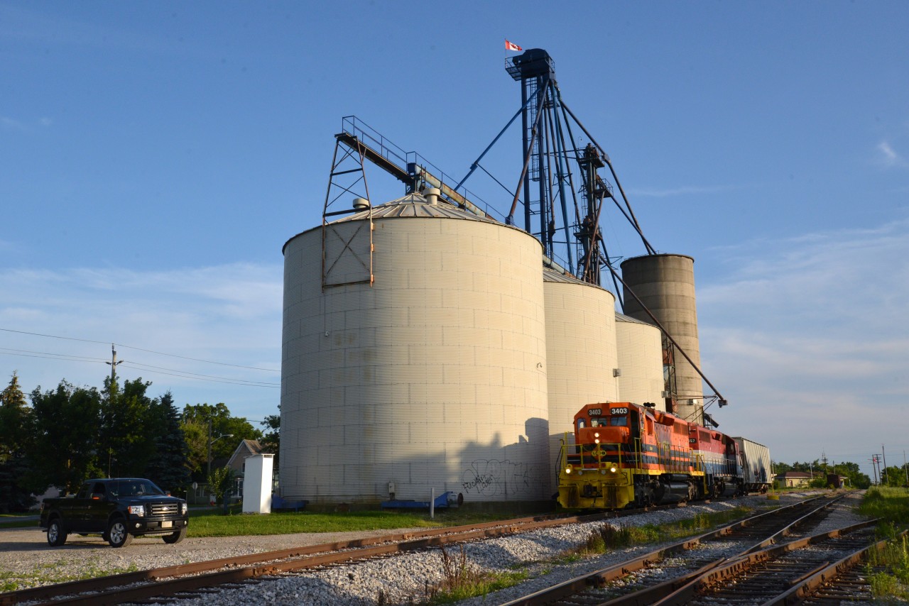 This photo (3rd of series) captures the first rail car inbound delivery to the Railview Trans Load facility serviced by siding #33 Hagersville Sub. With RLHH 3403 in the lead, RLK 4057 became the first locomotive to roll its wheels onto the new siding on July 5th, 2015 at 7:45 p.m. These two familiar power units dropped RLHH 597 south of town prior to spotting the single car loaded with millet placing one bay directly over the pit.  The contents of RLOX 60233 would be conveniently and quickly transloaded the next day into three trucks for Armstrong Milling Co. Ltd, Nelles Corners (Supplier of Canada's Premier Bird Feed). In the foreground, siding #40 veers off of the main to the right and in the far background an interesting relic continues to rust away amidst undergrowth.  It is a lonely memory from years past and reportedly last used for storage purposes.  The relic has an interesting / older type undercarriage and one can still albeit barely make out the 1943 CN logo that of a superimposed tilted wafer with wording Serves All Canada on a maple leaf (probably white in the day). It must be seen close up to be appreciated as all is lost / rust in a photo.  Lots of rail related activiey in Hagersville these days!