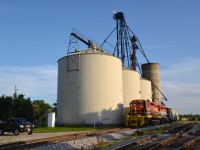 This photo (3rd of series) captures the first rail car inbound delivery to the Railview Trans Load facility serviced by siding #33 Hagersville Sub. With RLHH 3403 in the lead, RLK 4057 became the first locomotive to roll its wheels onto the new siding on July 5th, 2015 at 7:45 p.m. These two familiar power units dropped RLHH 597 south of town prior to spotting the single car loaded with millet placing one bay directly over the pit.  The contents of RLOX 60233 would be conveniently and quickly transloaded the next day into three trucks for Armstrong Milling Co. Ltd, Nelles Corners (Supplier of Canada's Premier Bird Feed). In the foreground, siding #40 veers off of the main to the right and in the far background an interesting relic continues to rust away amidst undergrowth.  It is a lonely memory from years past and reportedly last used for storage purposes.  The relic has an interesting / older type undercarriage and one can still albeit barely make out the 1943 CN logo that of a superimposed tilted wafer with wording Serves All Canada on a maple leaf (probably white in the day). It must be seen close up to be appreciated as all is lost / rust in a photo.  Lots of rail related activiey in Hagersville these days!
