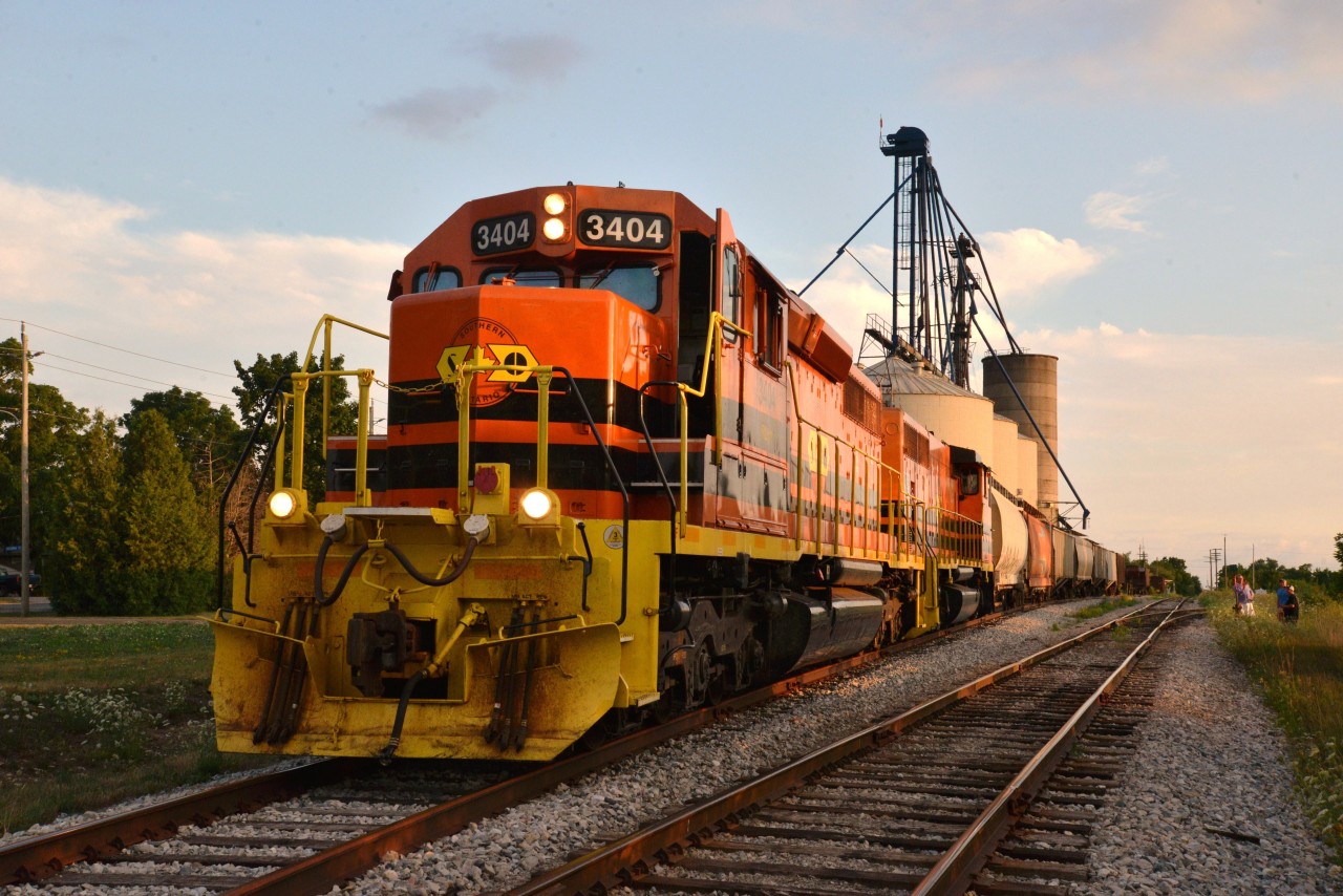 This is the 2nd photo of a proposed short series featuring Southern Ontario Railway (SOR) and the outbound kick-off of Railview's Trans Loading Services at Hagersville.  RLHH 597 with RLHH 3404 (lead) and RLHH 3409 are seen idling on siding #33 and soon to depart with the first outbound shipment of grain cars loaded with this years local grown wheat.  AEX 14952 grabs the honour of being the first grain car of the Railview consignment, arriving from southern USA via Fort Erie, to be loaded here with 90 ton of Haldimand County grown wheat.  CN Hagersville's signage is in the background and a few of the Mattice family can be seen in the foreground also capturing the moment.  This enterprise should attract a measure of local interest for years to come.  In fact and as I am adding text, I hear this night's nocturnal RLHH 597 rumbling through town and along side Railview elevators just a block away ... music to a railfan's ears.