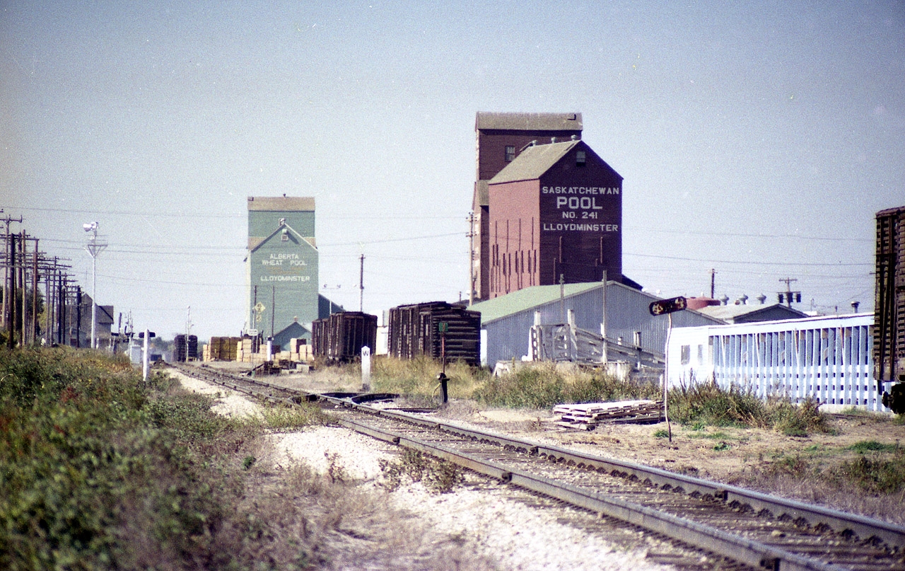 Now this is a unique part of Canada. I took a stab at location and road of this scene best I could, but it has been a long time. Lloydminster; probably the only city in North America that straddles two different jurisdictions.  Sure, there are examples like Kansas City, Kansas, and Kansas City, Missouri, but they are twin cities, whereas Lloydminster is the same city, but straddling two provinces. Where else could you see two grain elevators so close yet different provinces? Makes me wonder if either of them still exist. Along what I believe is the CN line, there is the station. What province is it in? I do not know. Need a Westerner familiar with the area to give us a rundown on just what is what. An interesting old photo though, and despite lack of a moving train, one of my favourite shots from bygone days. Years ago, most of the citizens lived on the Saskatchewan side, now 2/3 are on the Alberta side. AB charges only federal GST, SK also has a PST. To make it all fair, the whole city does not collect a PST within its limits.  Quite the place.