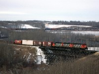 This is the Westlock Sub, just north of Edmonton, where it crosses the Sturgeon River. The train is the daily (or near daily) southbound manifest from McLennan.
This train is hauling wood products on the front, and on the rear we see grain and chemical/petroleum cars. But what is most interesting are the gondola and ore cars. I seem to recall that these would come from Hay River NWT and they are a metal concentrate. It would be shipped to Calgary, and ultimately to the smelter at Trail BC. I seem to recall seeing this material on train #484 from Edmonton to Calgary.
Note the caboose passing some ballast cars. That siding is no longer there.
....and what is that ribbed thing on the bank of the trestle abutment? 
