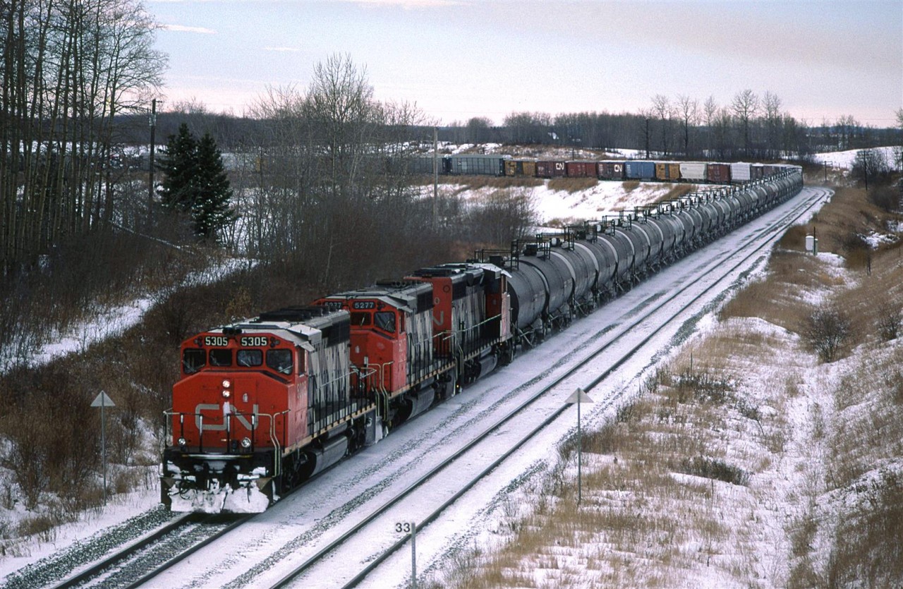 Although I did not hear it on the radio, I am virtually certain that this is train #218. The Tank cars and auto racks are pretty much a dead giveaway. 
Carvel is an interesting spot in that there is a large, relatively tight S curve in the tracks, some useful topography and nice scenery. On top of that, it is less than an hour outside Edmonton. This view is from the highway bridge, looking west. The train is wrapped around the curve to the south. Just out of frame, the curve reverses and the tracks continue west.
