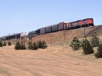 218 is close to arriving at east Edmonton's Clover Bar yard where CN likes to keep most of the hazardous materials, and where they have an automobile transfer yard. Both those types of loads are a dead giveaway that this is train #218.
It is seen on the embankment for the approach to the high bridge over the North Saskatchewan River.
Some of the efforts for Edmonton's beautification projects can be seen in the foreground. 
