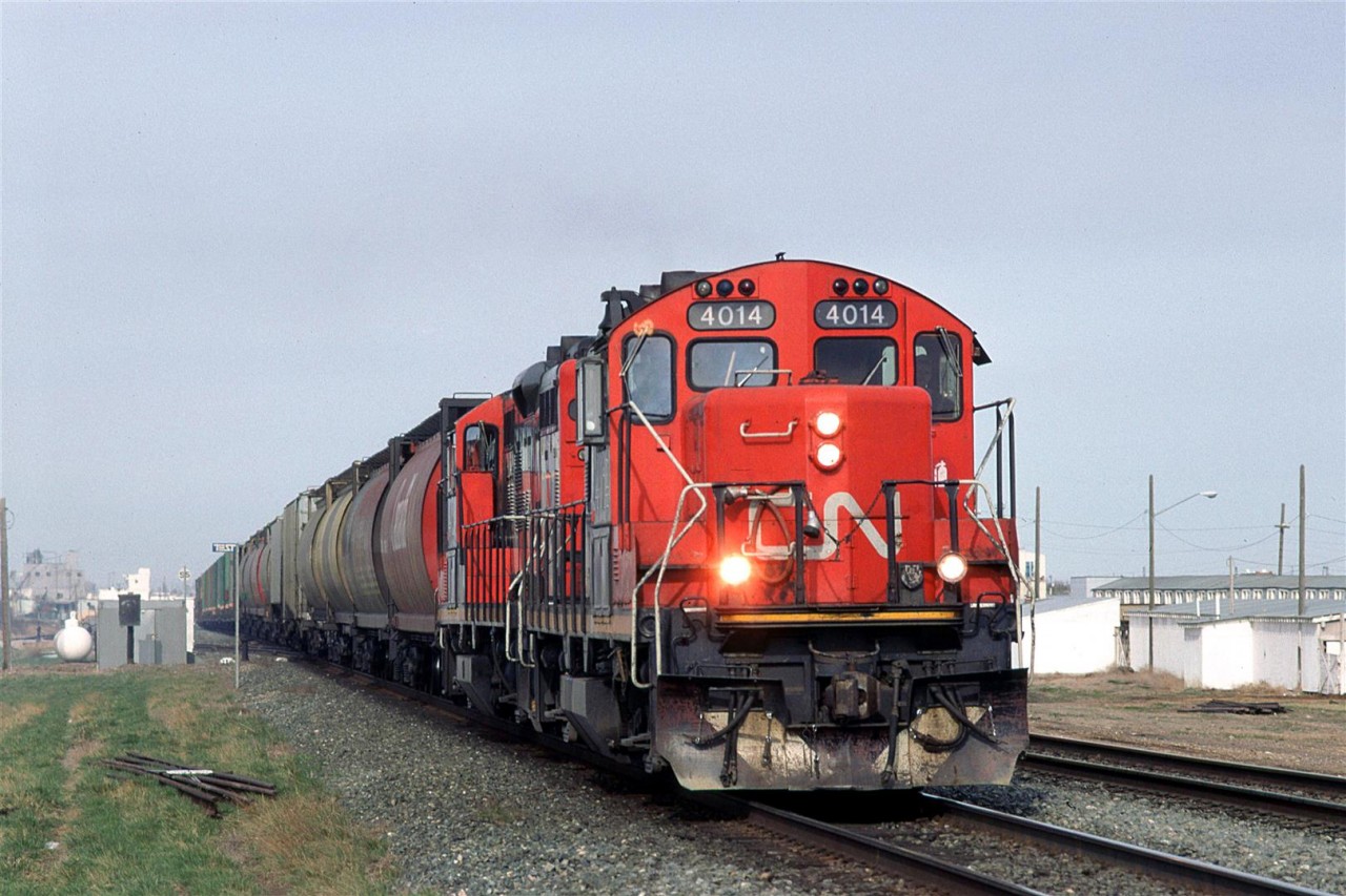 520 rolls out of Calder/Walker Yard in Edmonton and down the Wainwright Sub, toward Bretville Junction, where it will veer right down the Camrose Sub. It has grain empties for the elevators along the way and center beam lumber cars for a mill in Camrose.
The buildings to the right were for the stockyards that thrived at one time in NE Edmonton.
And the haze is likely smoke that blew in from forest fires.