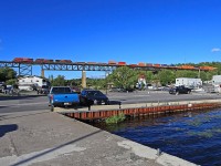 On our trip to Parry Sound last Monday we only were able to catch two northbounds on the CP trestle over the Seguin River. The first was a <a href="http://www.railpictures.ca/?attachment_id=25869"><b>short manifest</b></a> and just shy of two hours later this long stack train with three GEs up front and another as DPU about 2/3rds of the way back. this one snuck up on me as I was sitting on a picnic table in the shade. Judy had gone off wandering somewhere and left me in charge of 250-odd pounds of canine mighty hunters (their opinion, not necessarily the truth). When I finally did hear the train it was almost on the trestle. I grabbed the leashes and took off running to get to the docks along the river's edge for a clean view but the dogs both wanted to catch whatever it was I was chasing too. Unfortunately they both had different opinions as to what direction that mystery thing would be, and I got tripped up in the mayhem and only made it halfway there by the time I had to either make the shot or miss it. I knew there was no way I would get around the mooring lagoon in the foreground so I settled for this shot, although I would have preferred not to have the parking lot showing. Boats, river and a lighthouse would have made for a better foreground than cars and concrete! Oh well, ya can't win 'em all...