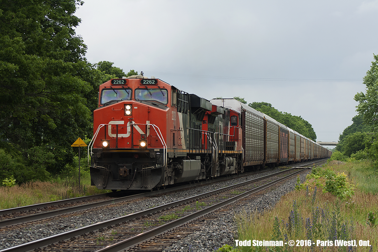 On a weird day weather wise, standing at a private driveway crossing in the rain...CN 2262 leads the charge of auto racks westbound past the yellow 'Paris West' sign (just to the left of the locomotive).