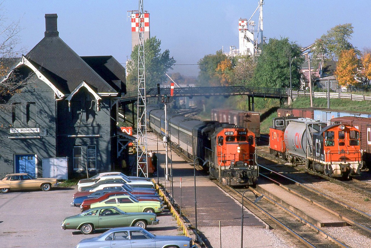 VIA train #86 behind CN GP40 4016 makes its station stop at Woodstock Station on October 14th 1977, while CN SW900 7222 switches cars in the background. At that time VIA was quite new, and timetables were joint VIA, CN and CP. Also of note in this scene is the colourful selection of now-vintage autos lined up in the station parking lot.

A pair of CN GP40's, 4016 and 4017 (later renumbered 9316 and 9317) were given high speed gearing in the 1970's for use on passenger trains in Southern Ontario. They could often be found in CN, VIA and even GO Transit passenger service.