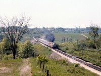 Under a cloud of MLW smoke from the trailing FPA2, The Canadian (#12) heads south after passing through Woodbridge, crossing over the Humber River bridge on Canadian Pacific's MacTier Sub. The train is approaching the white "Emery" mileboard sign, and the CN Halton Sub overpass northwest of Islington and Steeles from which this photo was taken. Sprawling farmer's fields line the right-of-way on both sides (with a private farm crossing a little further behind the rear "Park" dome-observation car).
<br><br>
The curve in the distance and Humber River bridge were part of the re-alignment of CP's MacTier Sub that took place circa 1907. The original Toronto, Grey & Bruce line curved through the valley of the river below, came to grade around the curve in the distance, and continued to Woodbridge on a more western alignment. The old Toronto Suburban Railway radial line from Weston to Woodbridge once ran through this area following the Humber River north, and also crossed below this bridge.
<br><br>
Today the MacTier Sub remains a busy CP freight corridor between Toronto and western Canada, but under VIA operation The Canadian was long ago shifted to CN routing in the southern Ontario area. Highway 407 ETR currently runs through the foreground of the photo parallel to CN's Halton Sub.