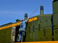 <b>Capping the stacks.</b> A volunteer at Exporail is capping the second of two stacks on CN 1382 after shutting down the engine and then pulling two buckets out of the long hood. The engine has just performed some switching moves.