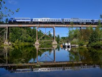 <b>Back in business, and reflected.</b> After not running during 2014 or 2015 (because one their dome car caught fire), the Orford Express has been running this summer. I finally got a chance to shoot it today at a classic location (the Eastman trestle) for the first time since 2013. Here the train is reflected in Lac d'Argent with FL9 OEXX 484 leading a 3 car train westwards over the trestle. In a minute the crew will change ends and the train will head east towards Sherbrooke.