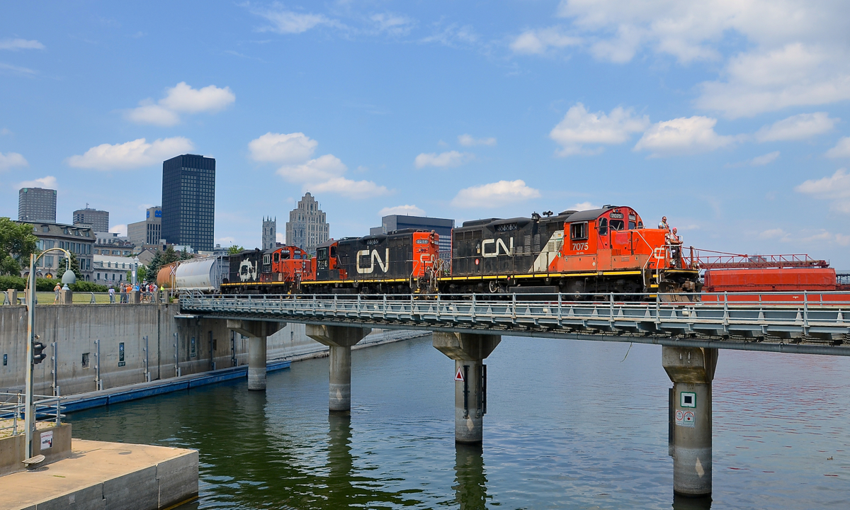 Three GP9's (CN 7075, CN 7256 & CN 7229) lead a short transfer out of the Port of Montreal as they cross the Lachine Canal today at lunchtime, seconds after the sun came out. While this job generally has two GP9's, three of them is very rare.