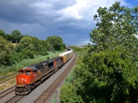 <b>Storm clouds in the background.</b> A short CN 401 (73 cars) only needs 6,300 GMD horsepower (SD70M-2 CN 8011 & GP38-2W CN 4806) as it passes through Montreal West with some nice storm clouds in the background. Where I was shooting from turned cloudy a couple of minutes later, so I lucked out.