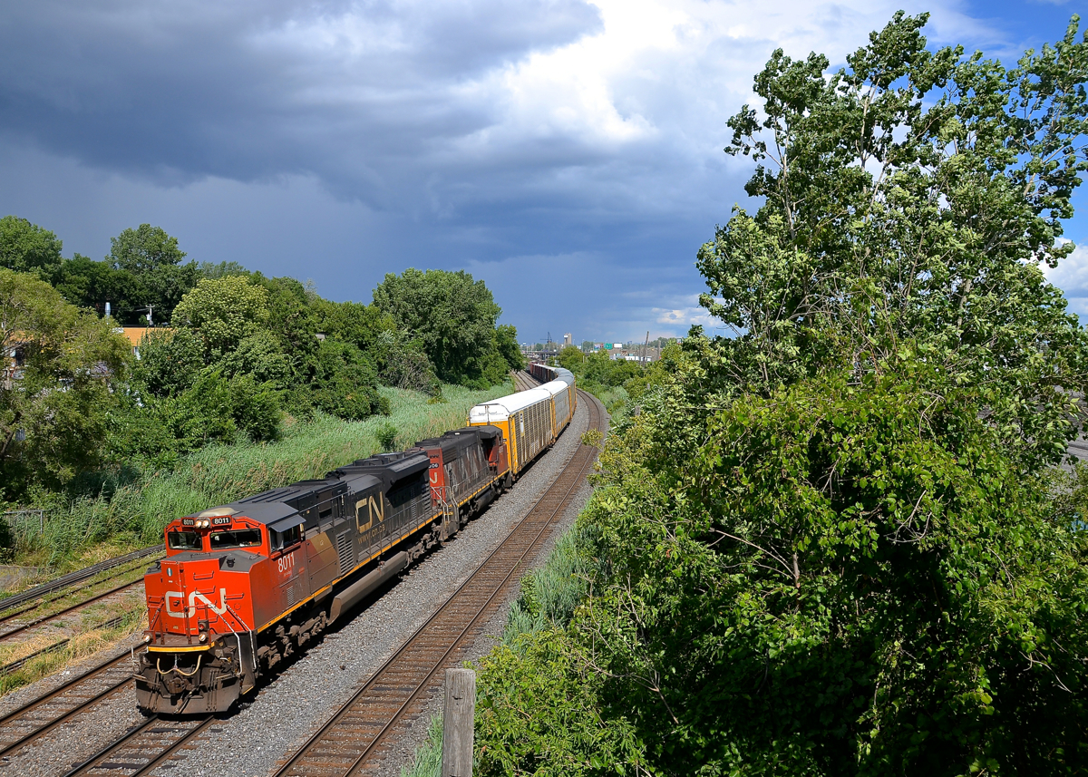 Storm clouds in the background. A short CN 401 (73 cars) only needs 6,300 GMD horsepower (SD70M-2 CN 8011 & GP38-2W CN 4806) as it passes through Montreal West with some nice storm clouds in the background. Where I was shooting from turned cloudy a couple of minutes later, so I lucked out.