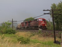 A mid afternoon shower has turned the air into something similar to that inside a sauna. The temperature is 30 but with the humidity it is closer to 40. The rain is still pouring down as the sun breaks through the clouds just in time for the passage of a westbound empty ethanol train. 