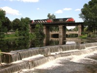 CN 2244 and CN 5540 striped with additional power parade CN 710 high atop the iconic bridge structure over the Napanee River adding grandeur to the picturesque Springside Park and peaceful waterfall.  In order to capture this angle to catch a eastbound and to include the whole of the waterfall, I camped (with permission) under shade on adjoining property owned by Gibbard Furniture, Canada's oldest furniture factory (at the time at least).  Employees gained a new perspective that day respecting patience, nearby beauty and railfanning.  
