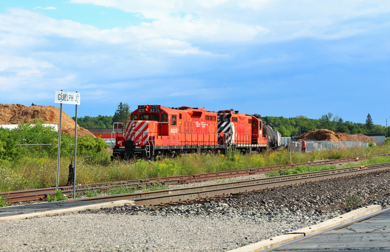With the sun shining bright to the west and dark clouds still hanging over the east, OSR 8235 with OSR 1591 power up to head out of the Goodfellow lumber yard at Guelph Junction and after making a stop in the office, will head to Guelph with the rest of their manifest.