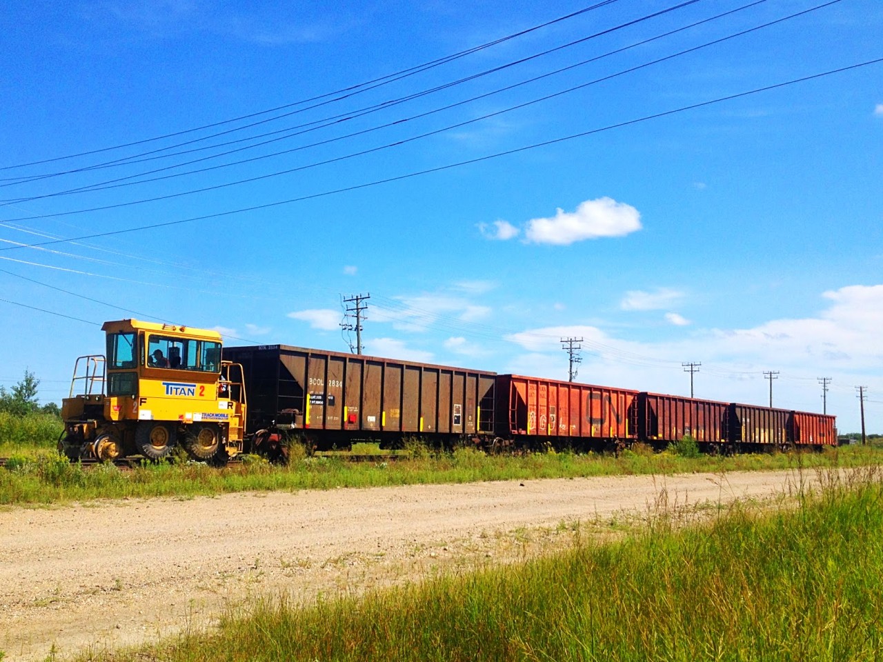 A trackmobile pulling 5 ballast hoppers on the Rivers Subdivision.