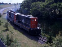 DOWNGRADE AT BOWRING PARK - Brake shoe smoke envelopes the head end power of Terra Transport Extra 926 East on the hot and humid Sunday afternoon of July 19, 1987. With only a few miles left to go on it's 547 mile  trans island journey, lead engine NF210 #926 and three sisters haul two CP rail boxcars and about twenty green inter-modal containers to it's final destination, the railyard in the capital city of St. John's. While travelling the 138 miles from Corner Brook to Bishops's Falls, a coach was added, thus making the former train known as #204, for that portion, Mixed Extra 926 East on the narrow gauge line.   