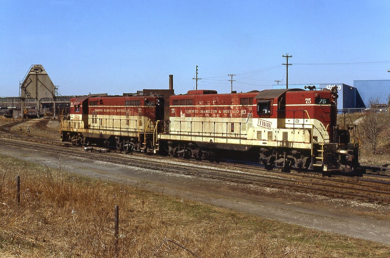 Looking a little worse for wear but still earning their keep, Toronto Hamilton & Buffalo GP7's 75 and 72 are pictured at the TH&B's Chatham Street shops in Hamilton. The well-known coaling tower from the steam days still stands in front of the turntable and roundhouse.

TH&B's Geep fleet, after being run until failures or retirements, would be rebuilt in parent CP's GP7/9 rebuild program as yard units. TH&B 75 and 72 would be sent for rebuild in 1987 and emerge in fresh action red paint as CP 1685 and 1682 respectively.