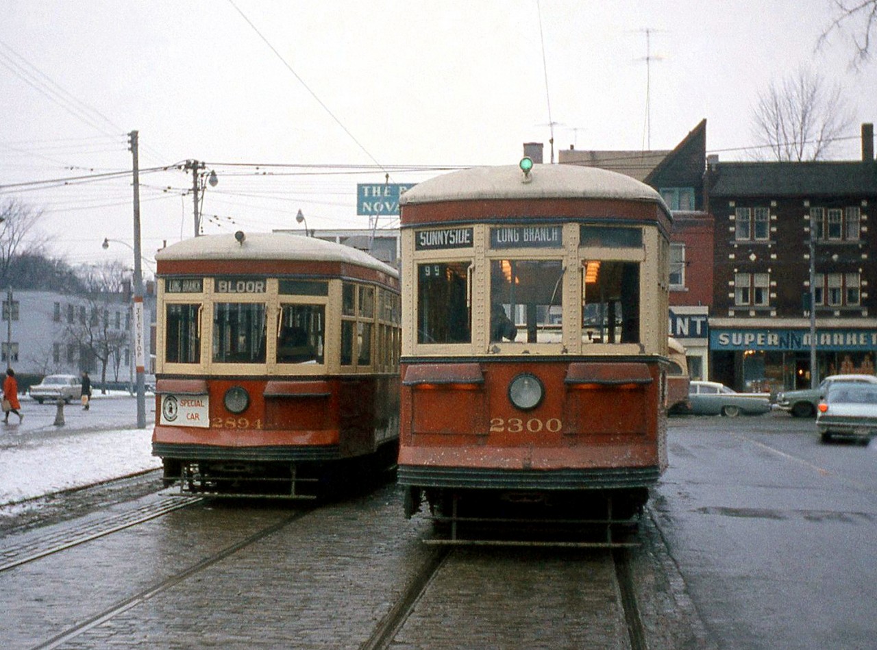 Two Peter Witt streetcars pose next to each other on an Upper Canada Railway Society charter on Spadina Avenue just south of Bloor Street: Toronto Transit Commission "Small Witt" 2894 is sitting facing the proper direction on the southbound tracks, while "Large Witt" 2300 is posed facing the opposite direction (south) on the northbound tracks.

The TTC's remaining Peter Witt cars were on borrowed time: the University subway line opening shortly would cut the number of streetcars needed for regular service, putting the oldest of the old (the Witts) into storage until their official retirement. A newer PCC car traveling westbound on Bloor is seen in the background, along with the Bank of Nova Scotia, Varsity Restaurant, and a Super NN Market lining the north side of Bloor.

More from that day's UCRS charter:
TTC 2894 and 2834 at Ferry Loop: http://www.railpictures.ca/?attachment_id=19956
The Peter Witts at College & Lansdowne: http://www.railpictures.ca/?attachment_id=24602
TTC 2300 posed at Eglinton Loop: http://www.railpictures.ca/?attachment_id=24456
Alternate view of 2300 at Spadina and Bloor:http://www.railpictures.ca/?attachment_id=24406