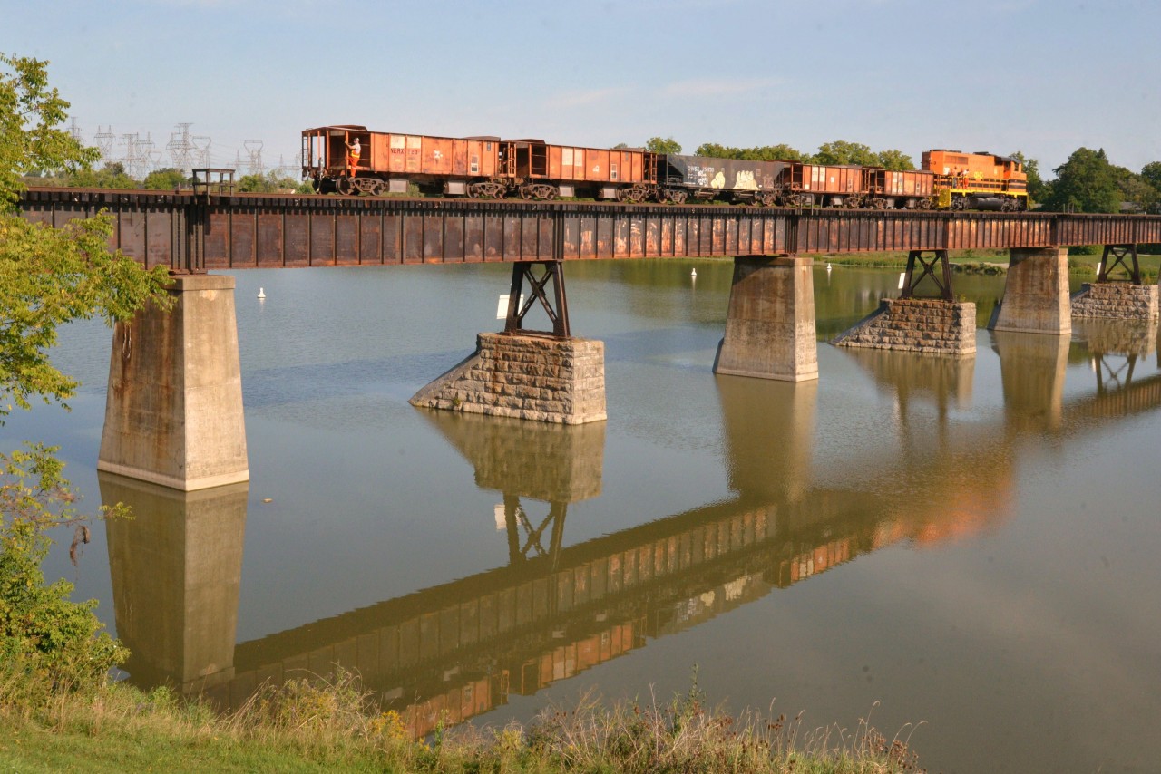 RLHH 3049 is now in push mode as the empty ballast train shoves backward south to the ballast base camp at Hagersville for reloading #2.  Note the four red-capped amigos standing behind the safety rail on RLHH 3049 and clearly enjoying the last two sunny hours before fall officially kicks in. Although on break, they blend in with livery colours while capitalizing on the birds eye view of the Grand, waterfall, flying honkers and fishing folk. The conductor of the day must have drawn the short straw given his uncomfortable southbound perch and corresponding sentinel duties. (third photo of three in series)