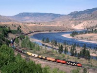 An eastbound empty grain train cruises up stream along the Thompson River below the village of Walhachin. Single units were often seen leading such trains out west.