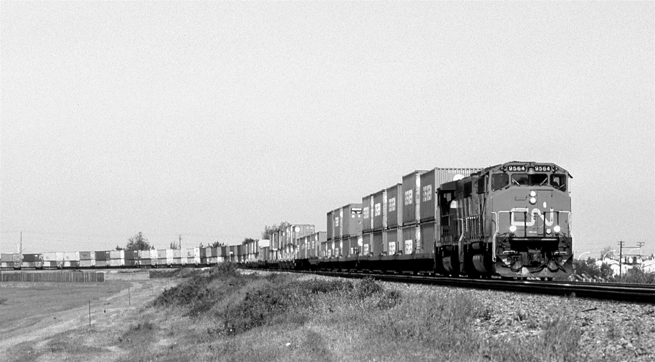 This is my very first photograph of a CN doublestack train. They had been running for years in the "States, but CN was a slow adapter. I had been too busy with my house renovation to do much railfanning for the last year or so, therefore I do not know when CN inaugurated DS service.
This is from one of those Kodakchrome rolls that would come back from processing with strange green hues. I, with my limited photo manipulation skills, was unable to achieve satisfactory colour results, so I simply removed all colour saturation.
Also, note that the pole line along the Wainwright Sub is now gone.